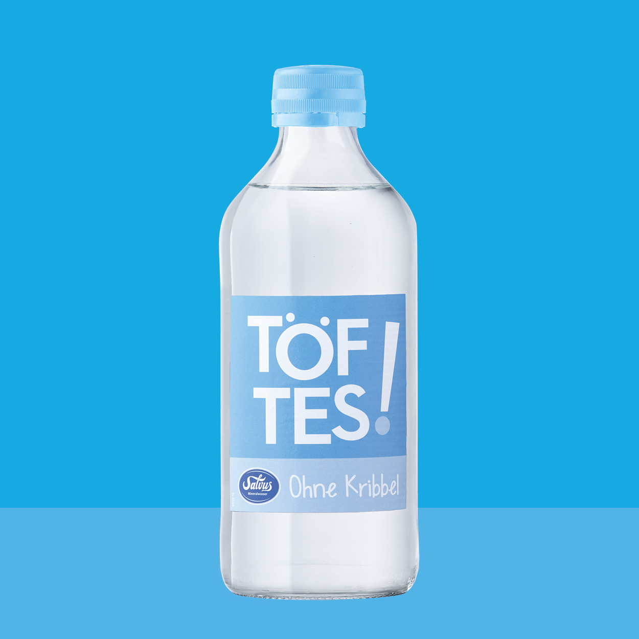 Töftes! Ohne Kribbel Flasche auf hellblauem Hintergrund passend zum Etikett.
