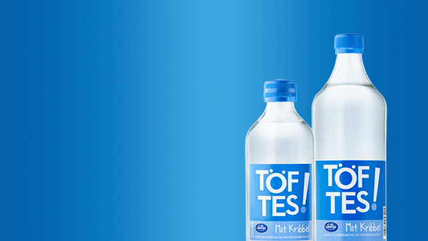Produktdarstellung der Töftes Mit Kribbel Produkte bestehend aus der 0,33 Liter und der 0,75 Liter Glasflasche.